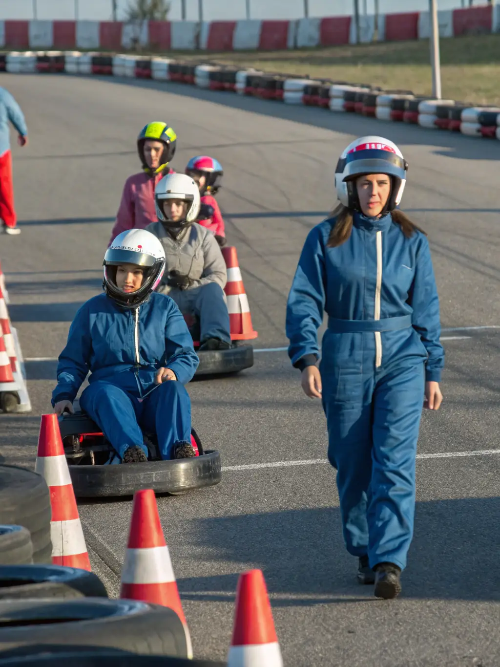 An image showcasing participants in a racing event, wearing safety gear and actively engaged in a motorsport activity on a professional track.